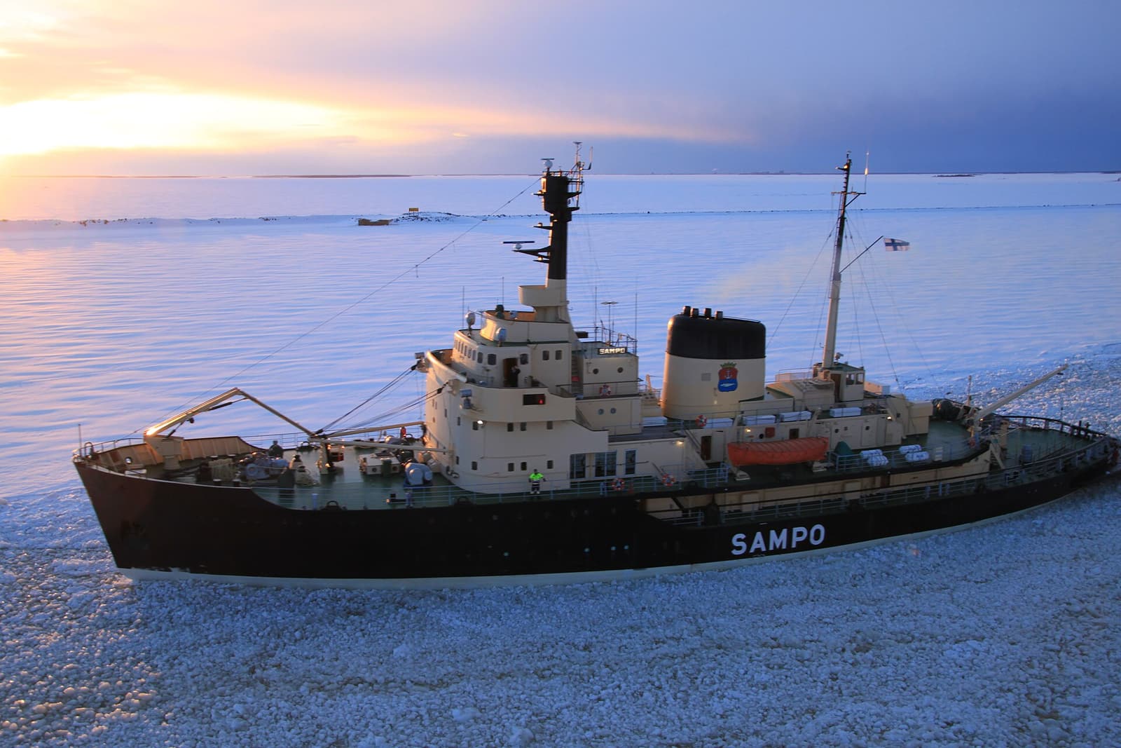 The black-hulled icebreaker Sampo in the frozen sea off Kemi at sunset