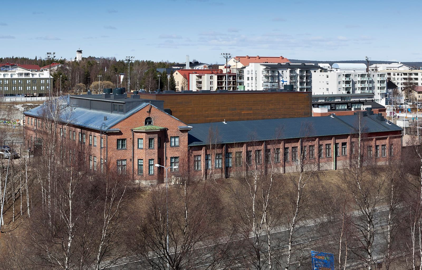 The red-brick Korundi House of Culture seen from above, with apartment blocks beyond