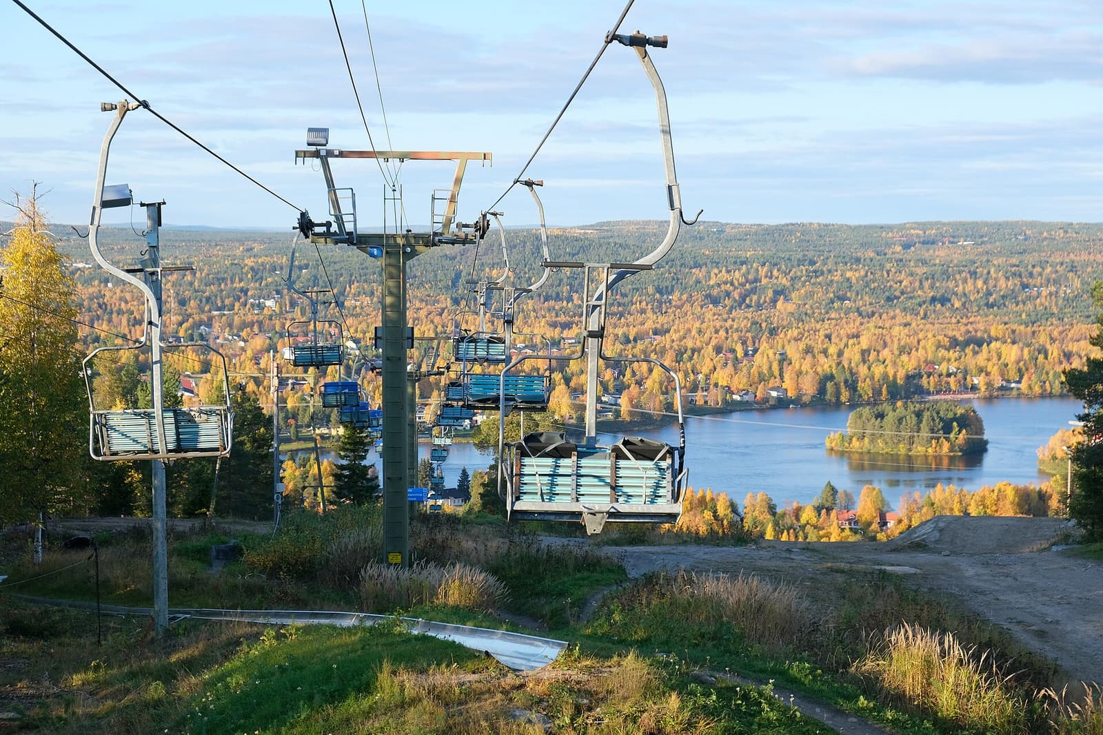 A chairlift on Ounasvaara above golden autumn forest, with the river below