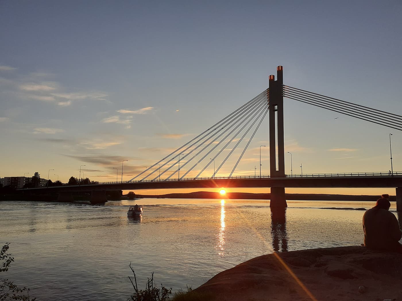 The midnight sun low over the Kemijoki river behind the Lumberjack’s Candle Bridge