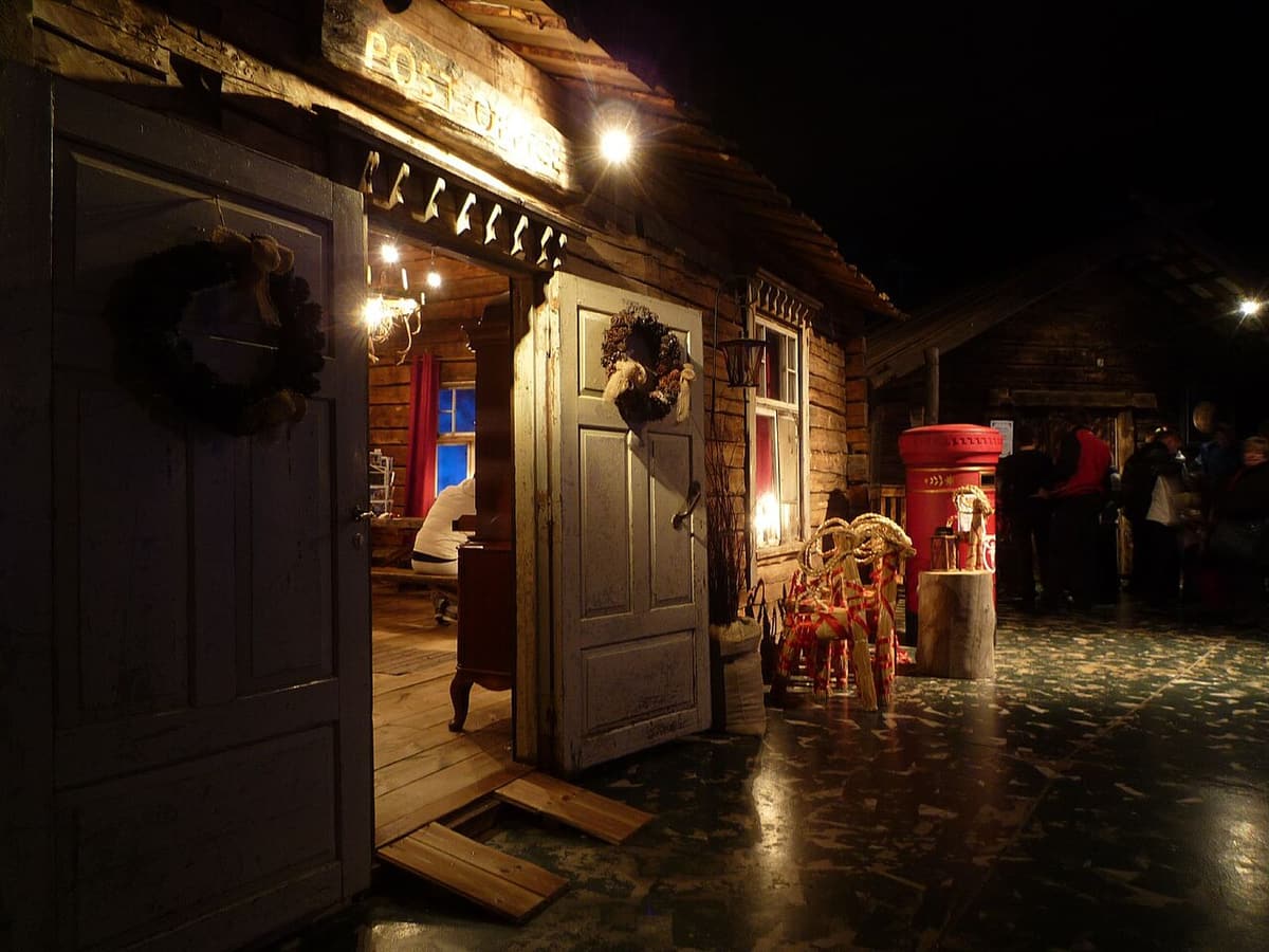 A candle-lit wooden cabin and red postbox inside SantaPark