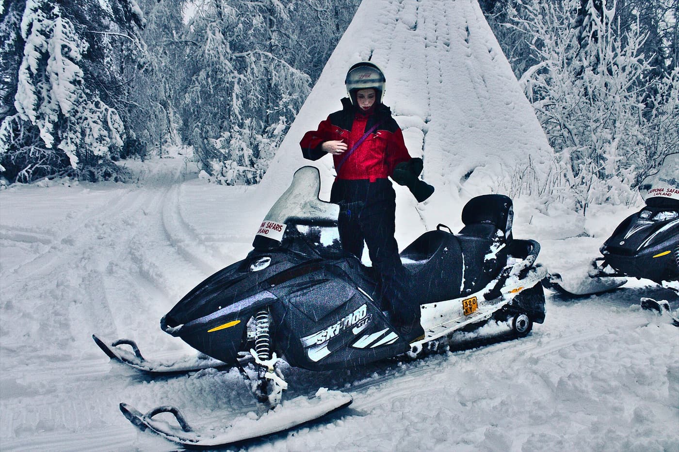 A rider on a snowmobile in front of a snow-covered tipi during a safari in Lapland